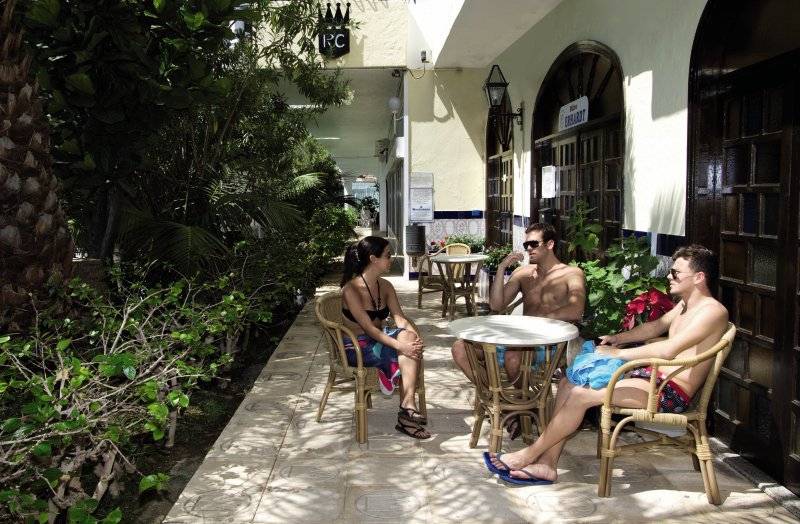 Drei Gäste sitzen auf der Terrasse des Hotels Rey Carlos und unterhalten sich.