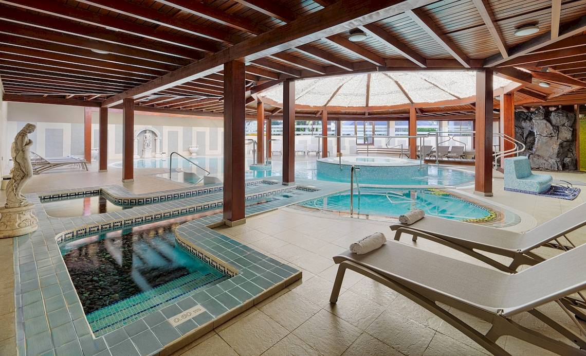 Innenpool des H10 Conquistador Hotels mit mehreren Becken und Liegestühlen.