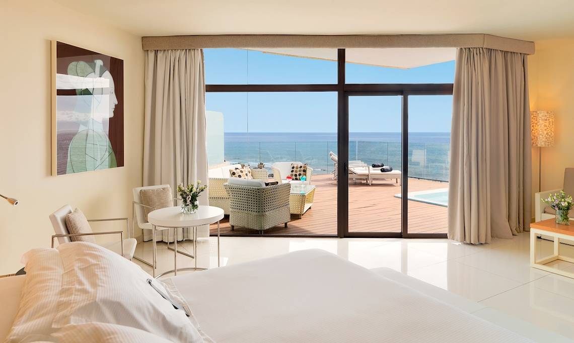 Suite im H10 Conquistador mit Meerblick, großem Bett und Terrassenmöbeln.
