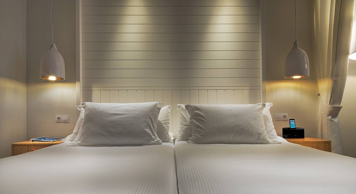 Doppelbettzimmer im H10 Conquistador Hotel mit weißen Laken, Kissen und Lampen.