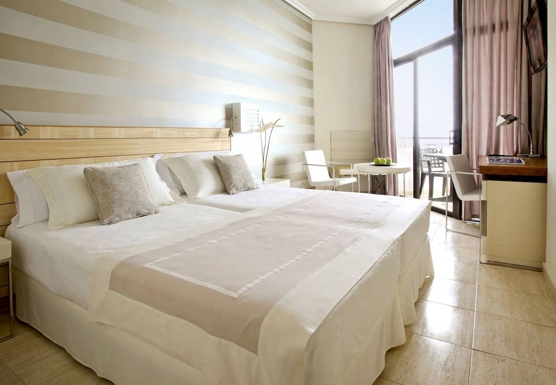Doppelbett-Zimmer im H10 Conquistador Hotel mit gestreiften Wänden und Blick auf den Ozean.