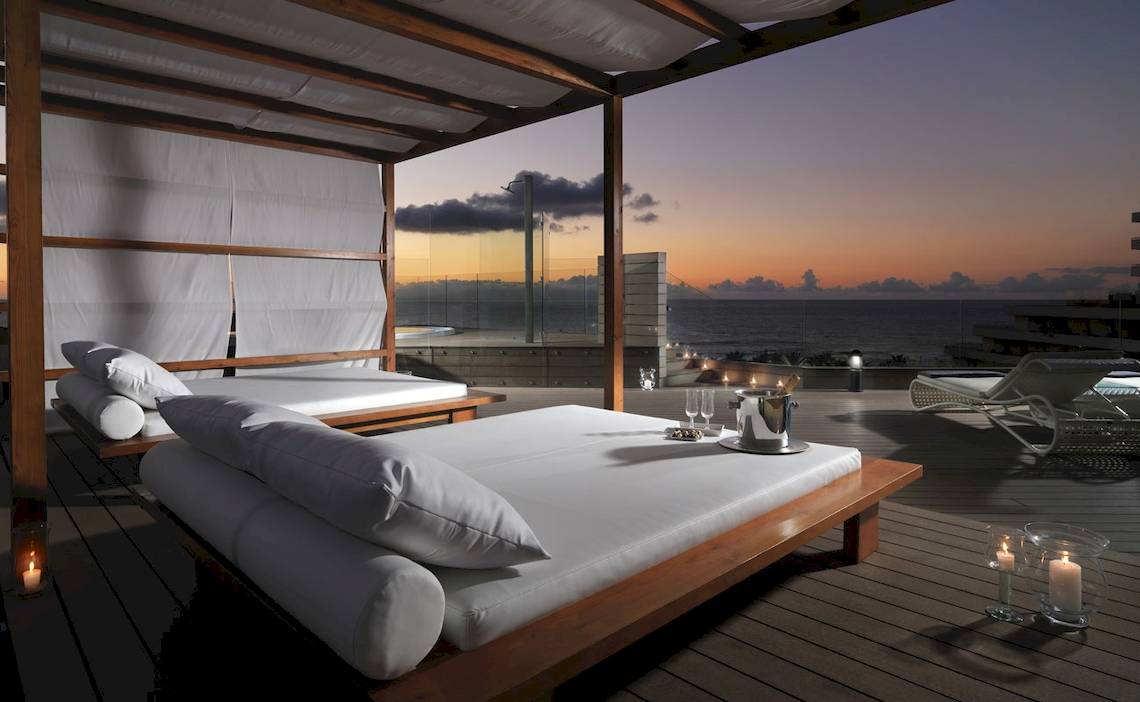 Terrasse des H10 Conquistador Hotels mit Betten, Kerzen und Meerblick.
