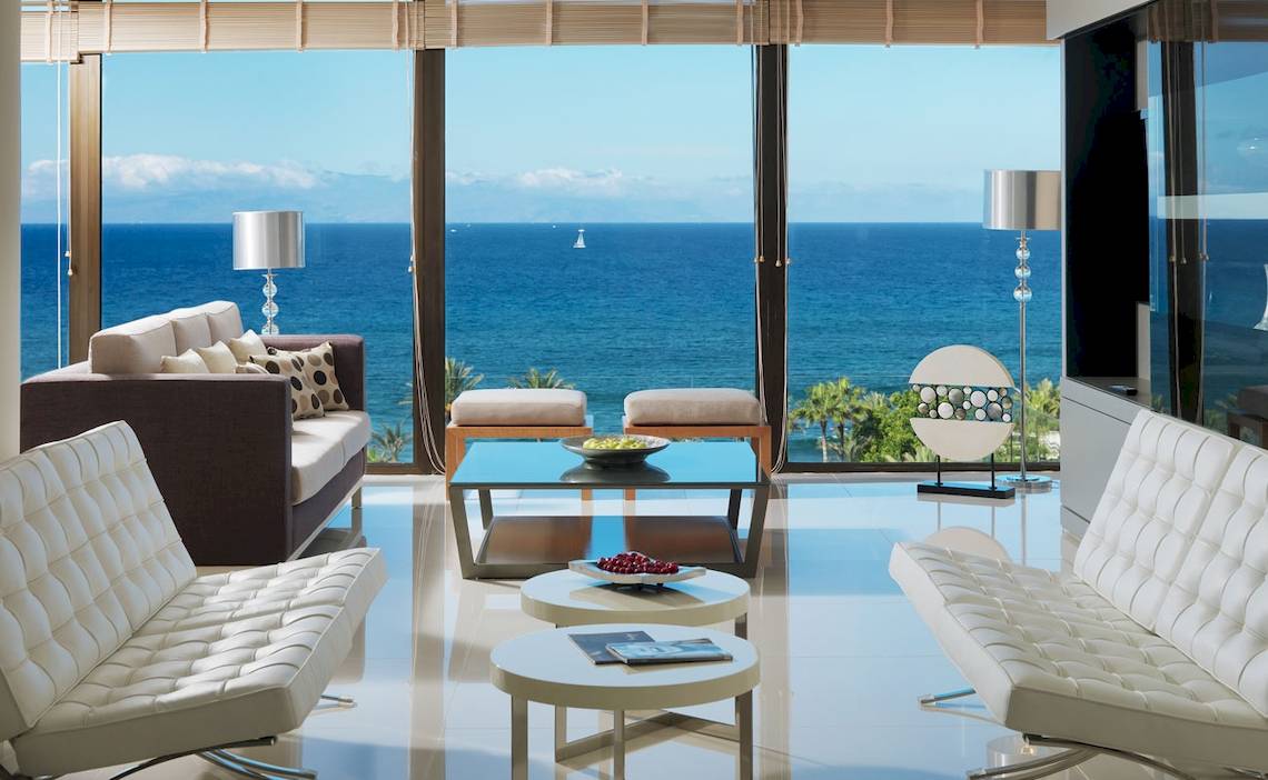 Wohnzimmer des H10 Conquistador Hotels mit Blick auf das Meer und einen Segelboot.
