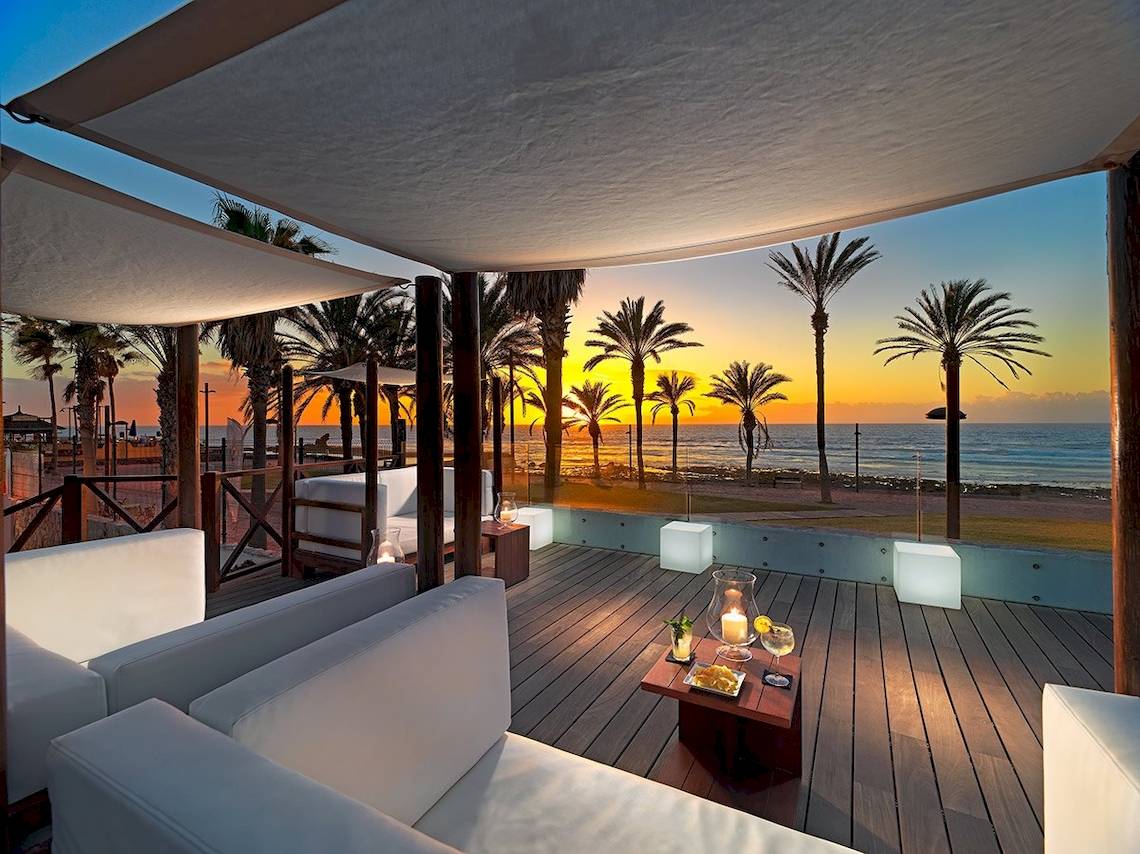 Terrasse des H10 Conquistador Hotels mit Blick auf den Sonnenuntergang und das Meer.