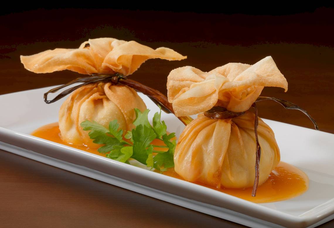 Zwei asiatische Gerichte auf einem weißen Teller mit Sauce und Gewürzen.