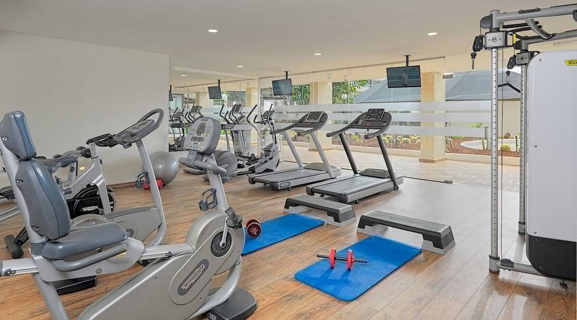 Fitnessstudio im H10 Conquistador Hotel mit verschiedenen Trainingsgeräten und Gewichten.
