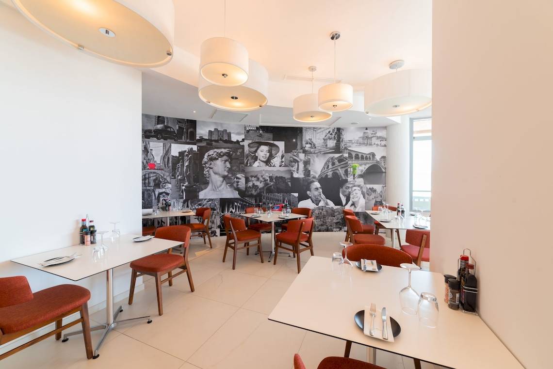 Innenansicht des Ramla Bay Resorts Restaurant mit einer Wand voller Fotocollagen.
