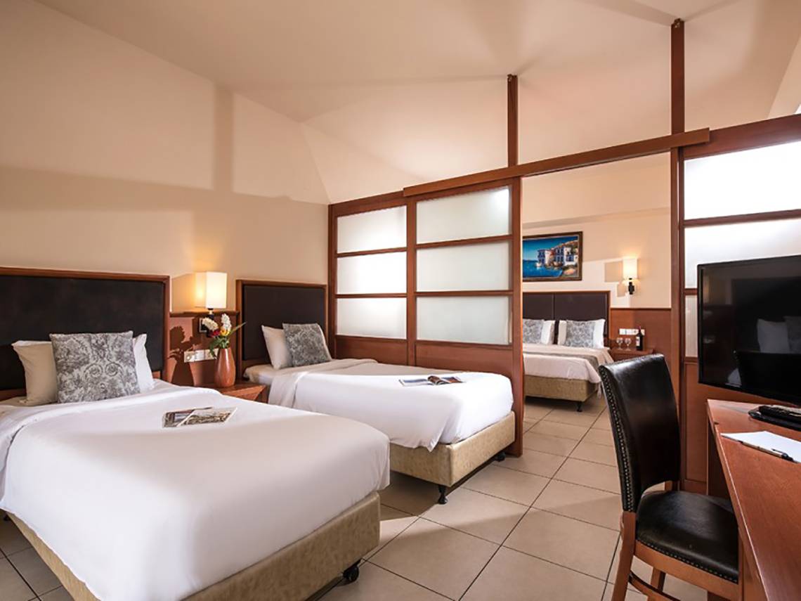 Doppelzimmer im Stella Palace Resort & Spa mit zwei Betten, Schreibtisch und Fernseher.