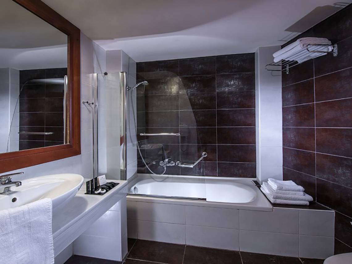 Badezimmer im Stella Palace Resort & Spa mit Badewanne, Dusche und Spiegel