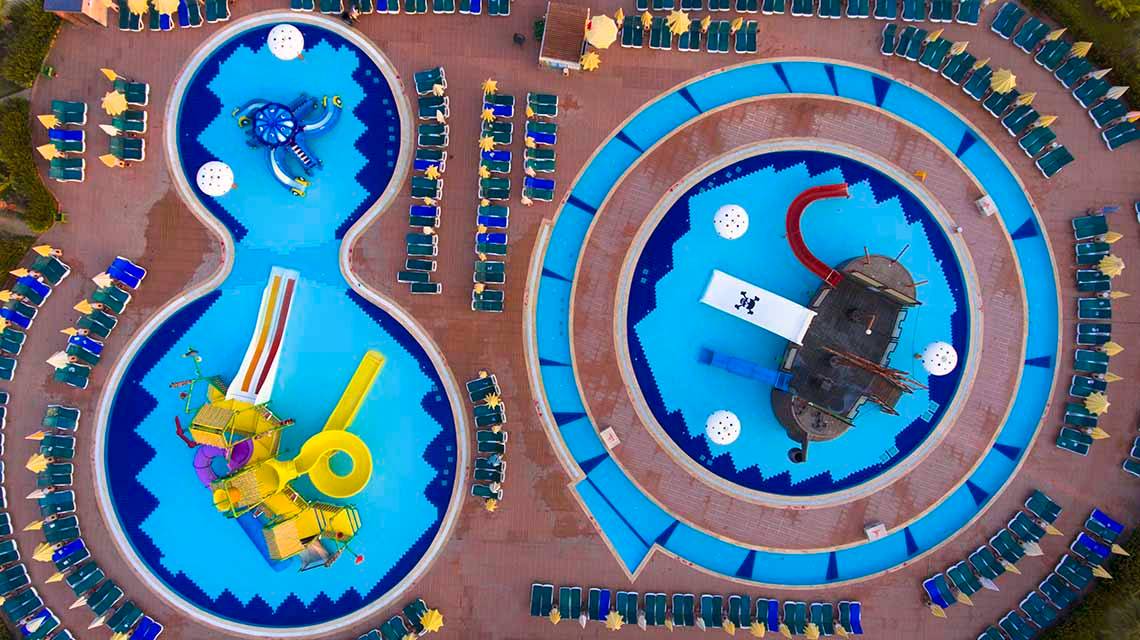 Luftaufnahme des Eftalia Holiday Village mit zwei Pools und vielen Liegen um sie herum.
