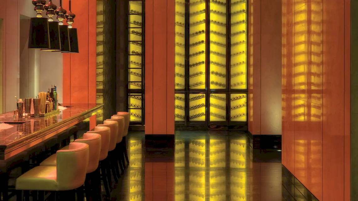 Barbereich des Park Hyatt Abu Dhabi Hotel & Villas mit roten Wänden und gelben Beleuchtung.