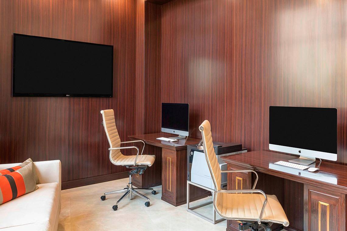 Arbeitsbereich im Le Royal Meridien Beach Resort mit zwei Schreibtischen, Monitoren und einer Couch.