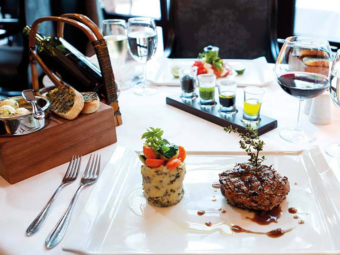 Gedecker Tisch im Paloma Oceana Hotel mit einem Gericht, Getränken und Zubehör.