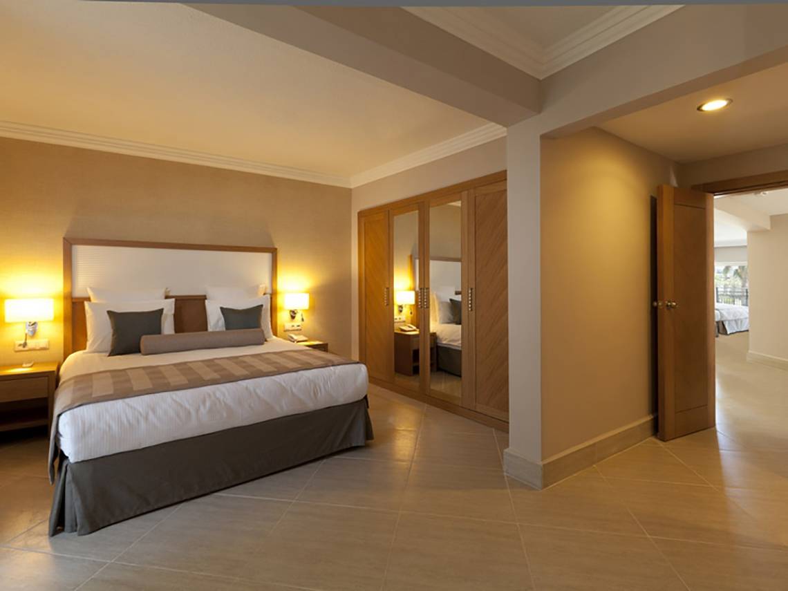 Innenansicht eines Schlafzimmers im Paloma Oceana Hotel mit Doppelbett, Nachttischen und Kleiderschrank.