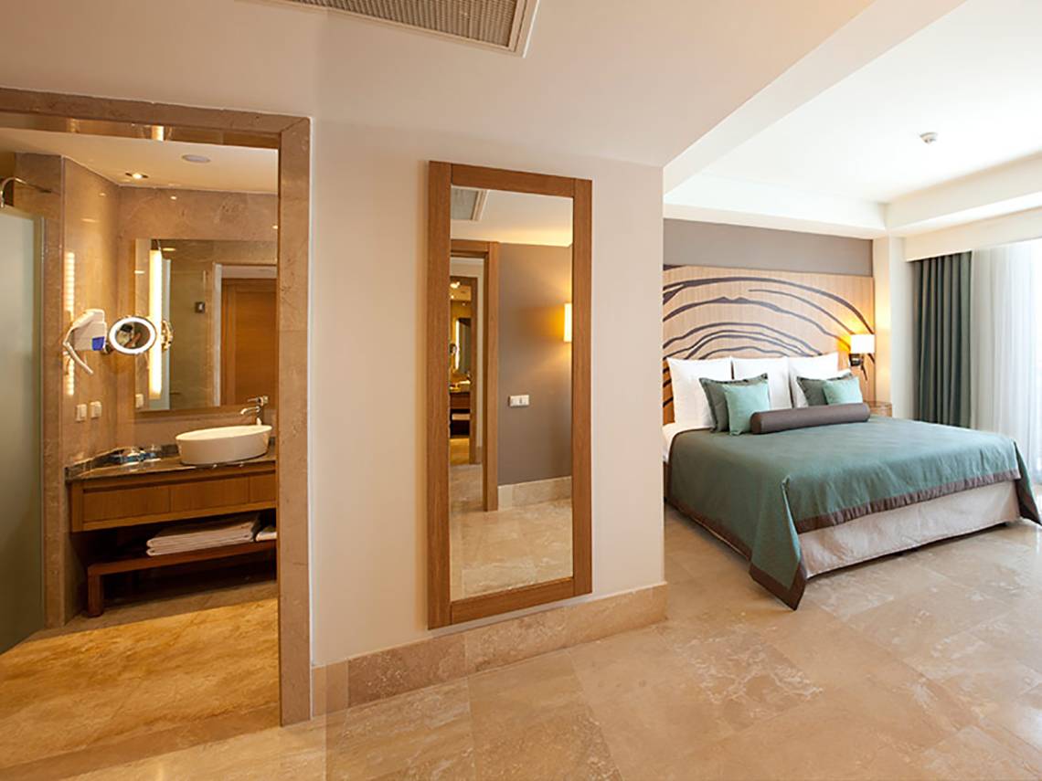 Innenansicht eines Schlafzimmers im Paloma Oceana Hotel mit Bett, Spiegel und Waschtisch.