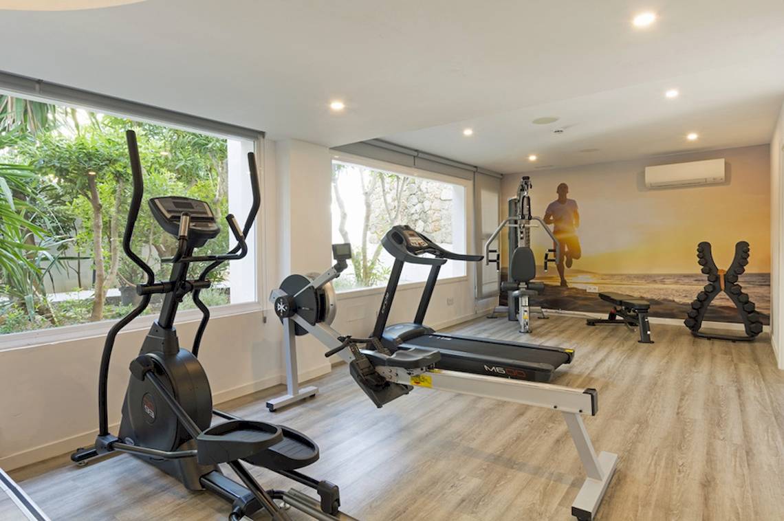 Fitnessbereich im HSM Golden Playa Hotel mit Geräten und Fenstern.