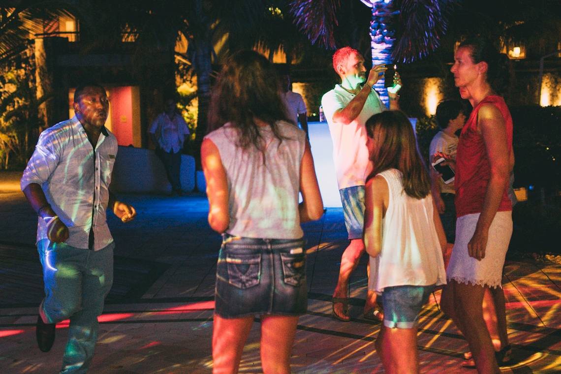 Feiernde Personen auf der Tanzfläche im Freien im Hotel Tamassa Bel Ombre bei Nacht.