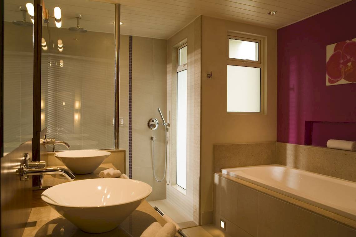 Badezimmer im Tamassa Bel Ombre Hotel mit zwei Waschbecken und einer Badewanne.