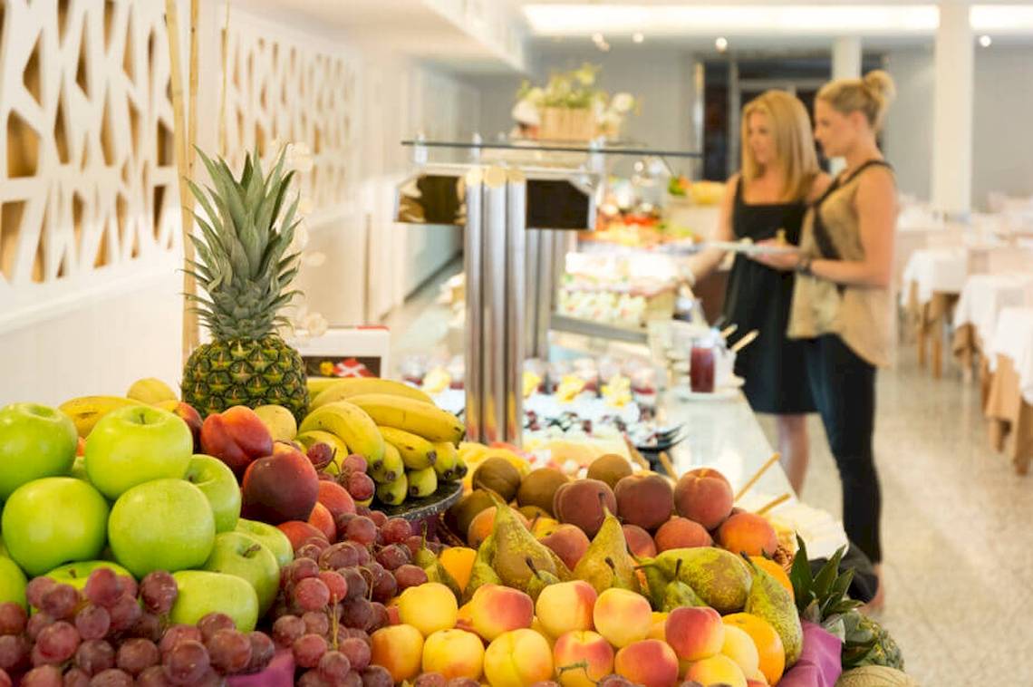 Buffet im HSM Golden Playa Hotel mit verschiedenen Früchten und zwei Frauen im Hintergrund.