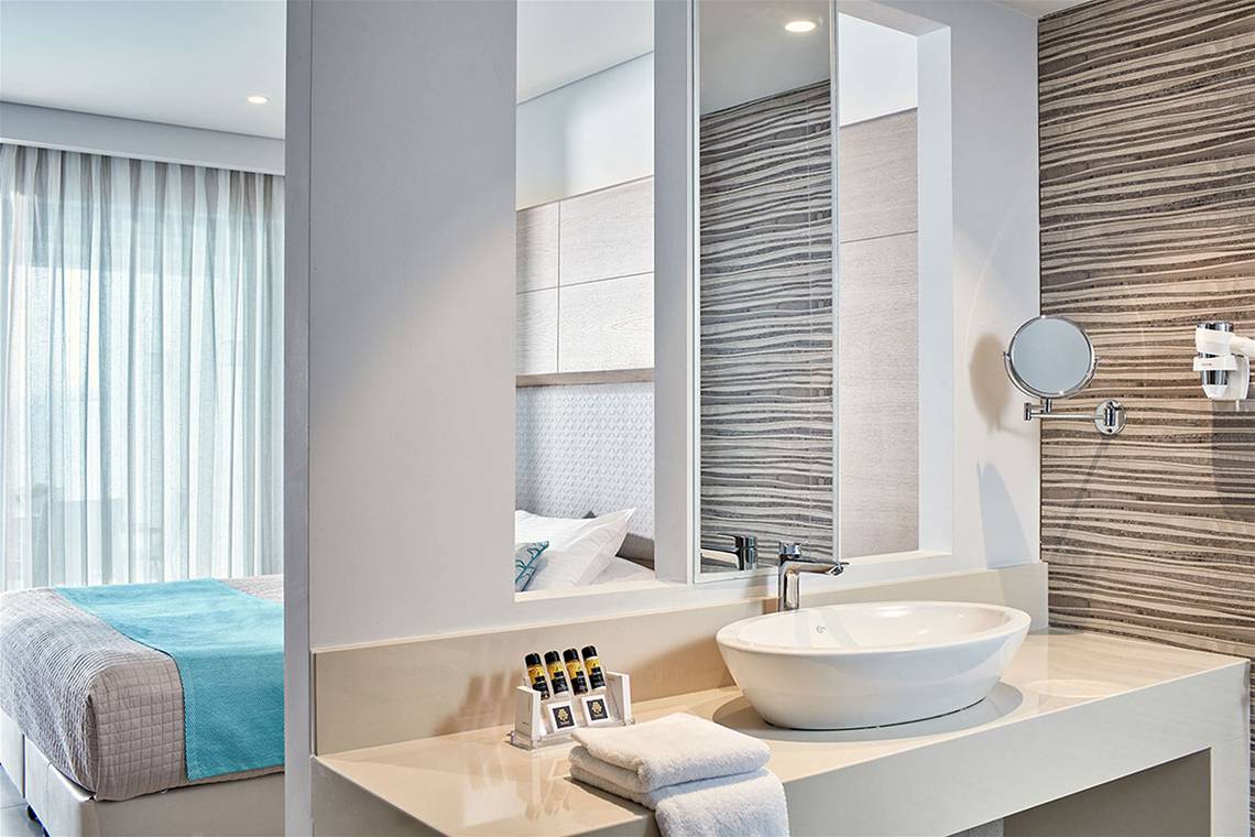 Badezimmer im Porto Bello Royal Hotel mit Doppelbett, Waschbecken und Spiegel.