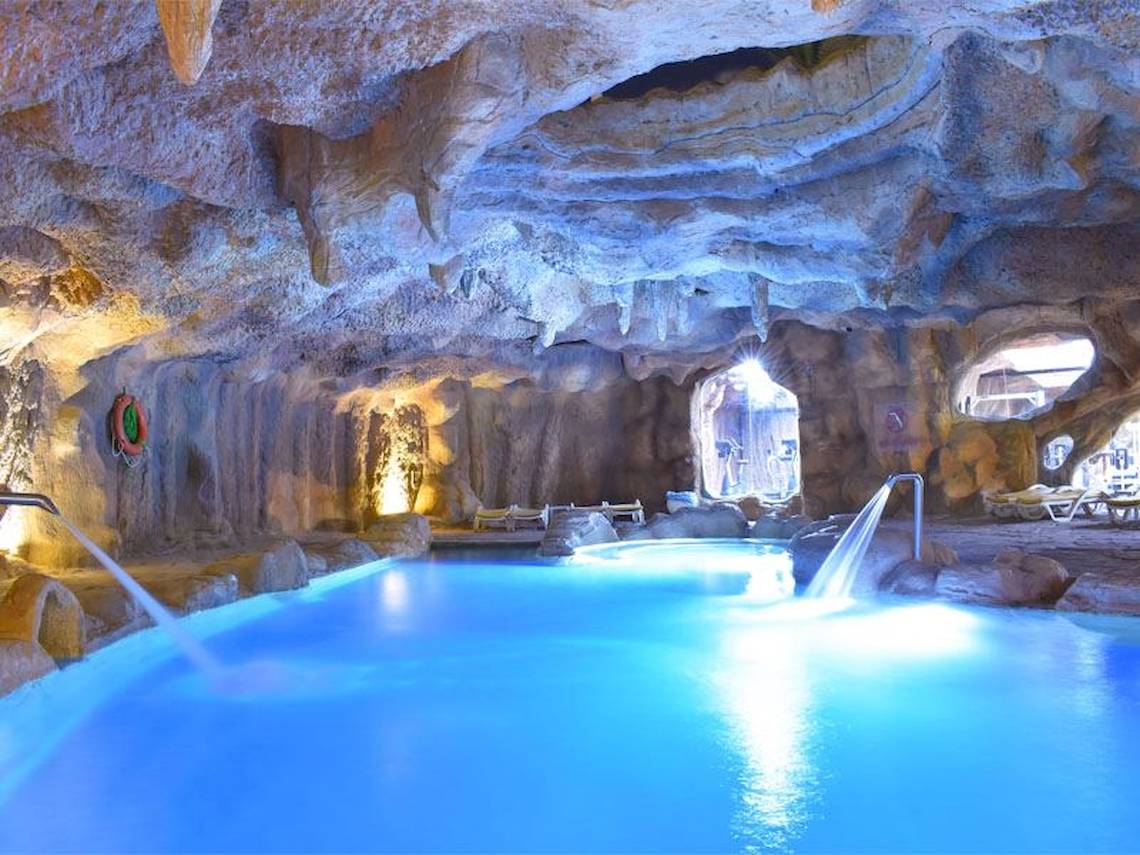 Unterirdischer Pool im Parrotel Beach Resort mit blau beleuchtetem Wasser und steinerner Decke.