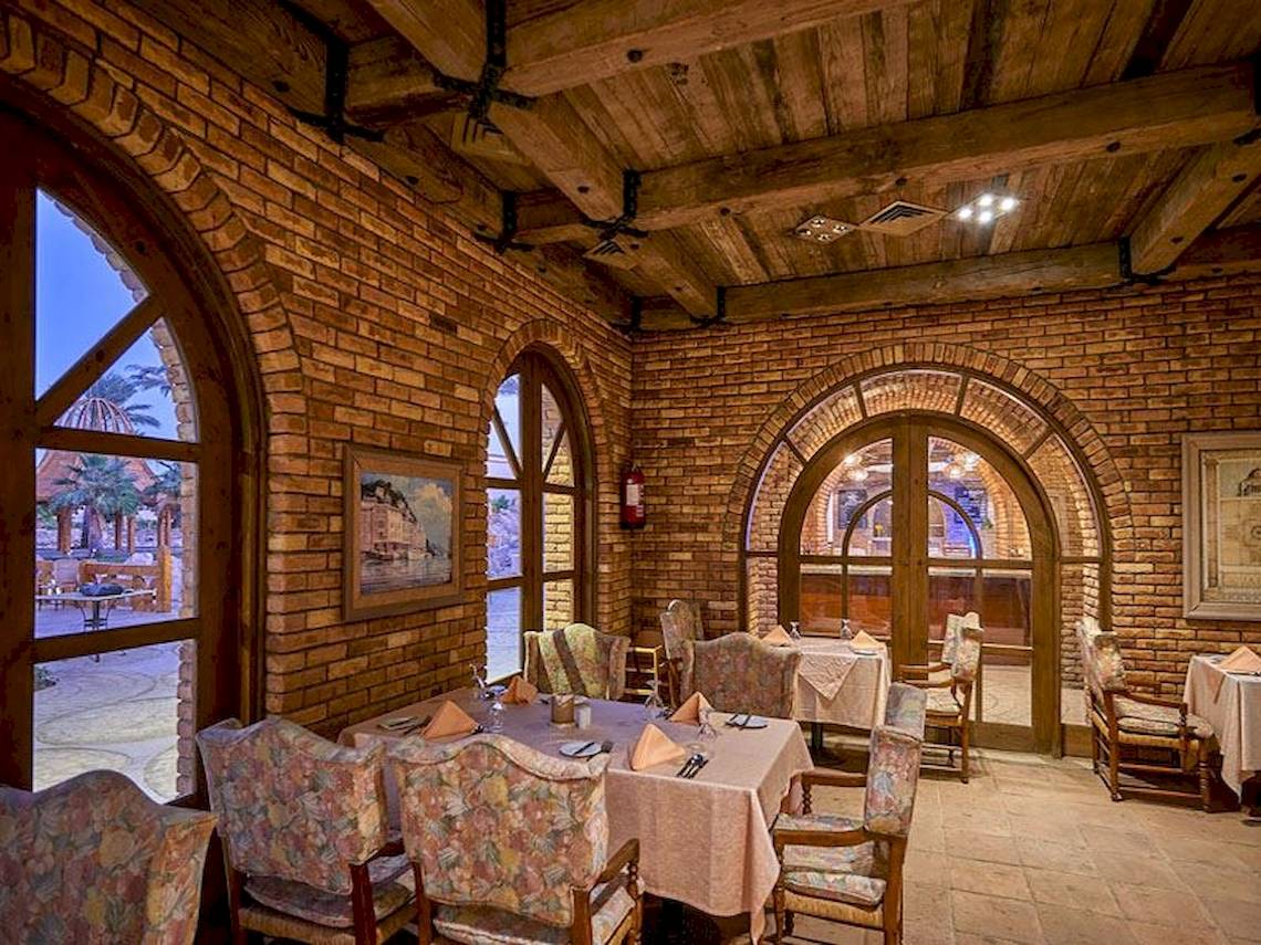 Innenansicht des Restaurants im Parrotel Beach Resort mit Holzdecken und Ziegelwänden.