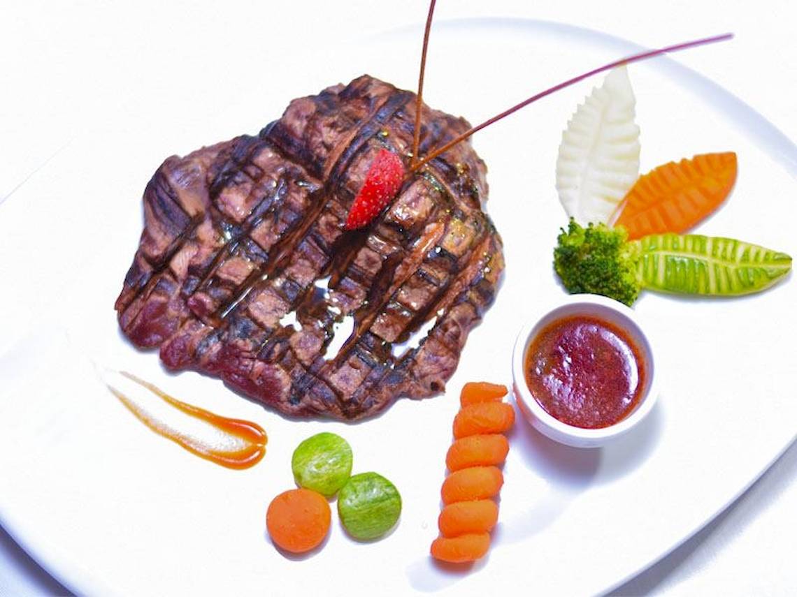 Gegrilltes Steak auf einem Teller mit Gemüse und Sauce.