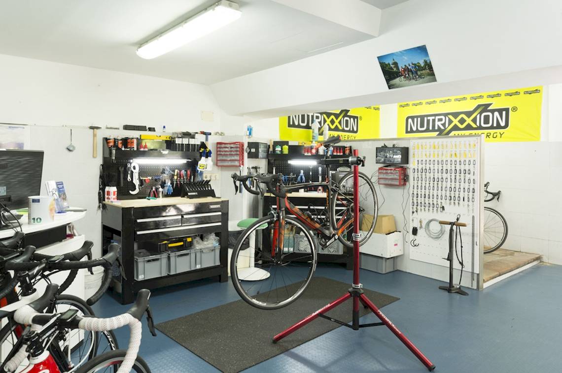 Ein Fahrrad-Reparaturbereich mit mehreren Fahrrädern, Werkzeugen und Bannern.