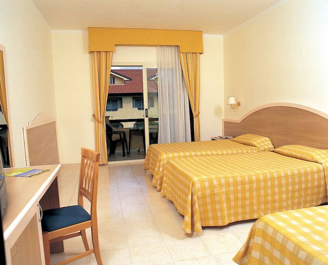 Doppelzimmer mit Balkon im Falkensteiner Club Funimation Garden Calabria, mit zwei Betten und einem Schreibtisch.