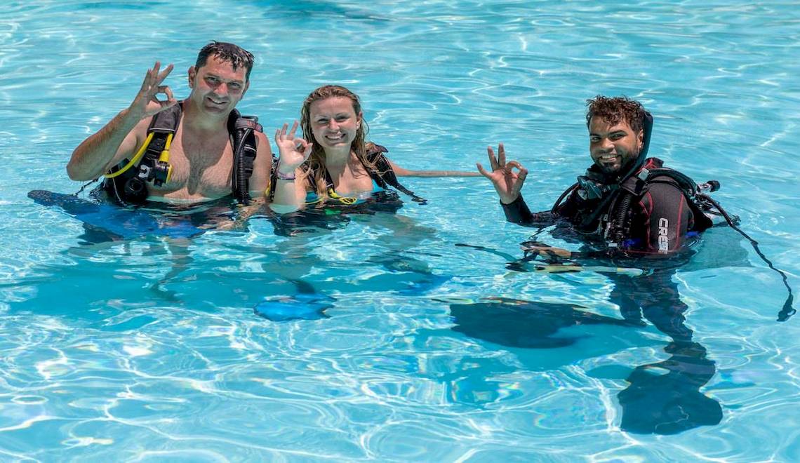 Drei Taucher im Schwimmbecken des Playabachata Spa Resort machen ein Friedenszeichen.