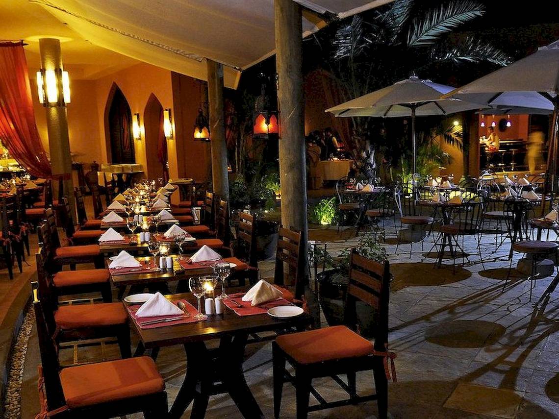 Außenbereich des SALT of Palmar Restaurants mit gedeckten Tischen und abendlicher Beleuchtung.