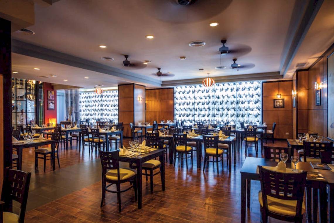 Innenansicht des Restaurants im Riu Cancun Hotel mit gedeckten Tischen und hängenden Lampen.