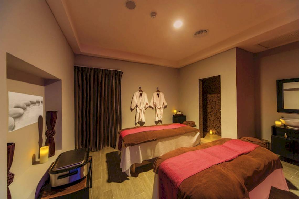 Massage-Lounge im Riu Cancun Hotel mit zwei Massagetischen, Robes und Kerzen.
