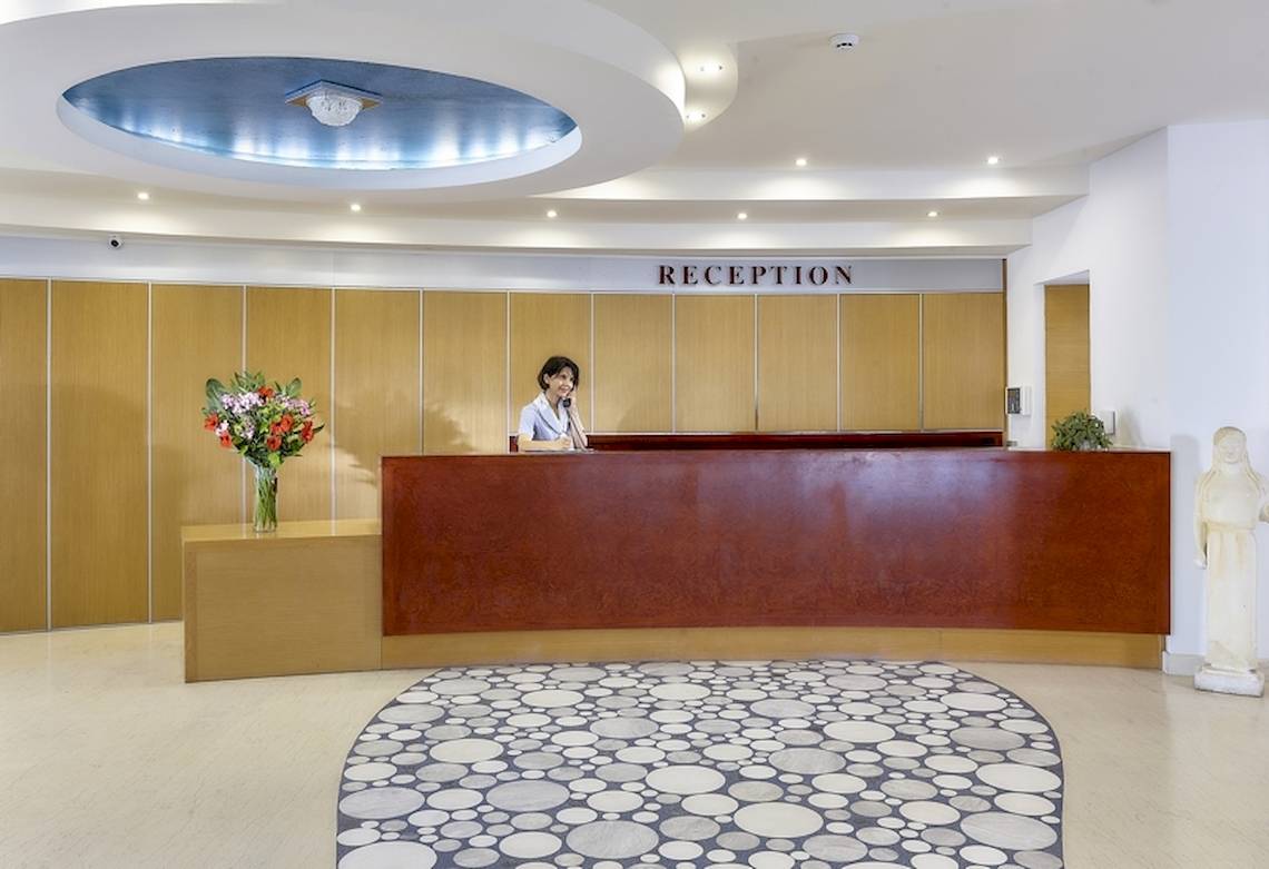 Empfangsbereich des Astir Beach Hotels in Kreta mit Rezeptionistin und Blumen.