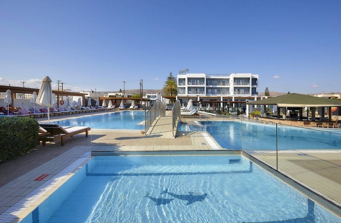 Außenpoolbereich des Astir Beach Hotels auf Kreta mit Sonnenliegen und klarem Wasser.