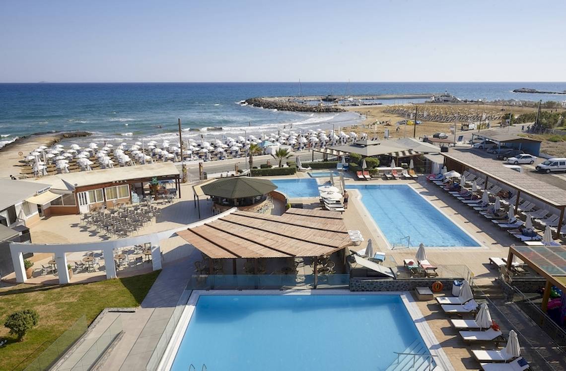 Luftaufnahme des Astir Beach - Kretas Resorts mit zwei Swimmingpools, Sonnenliegen und Sonnenschirmen am Strand.