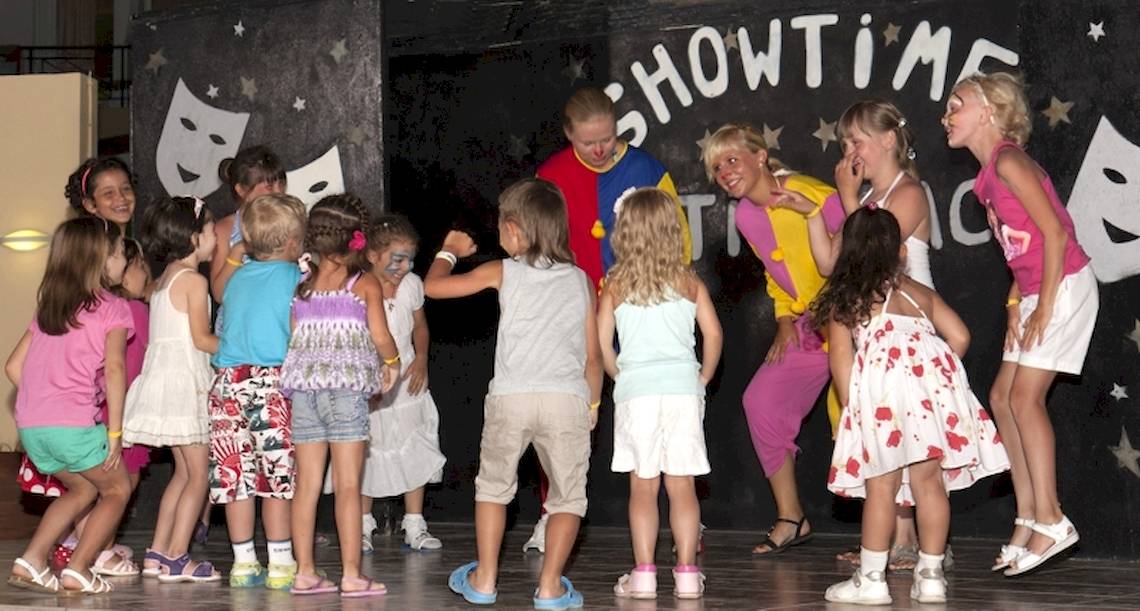 Gruppe von Kindern und zwei Erwachsenen in Showkostümen auf einer Bühne des Astir Beach Hotels in Kreta.
