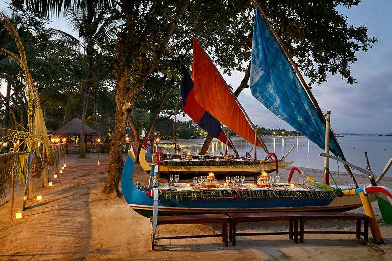 Abendessen auf einem Boot am Strand des Melia Bali Hotels bei Nacht.