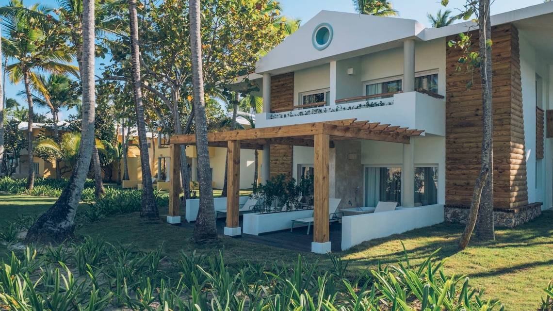 Außenansicht des Coral Level at Iberostar Selection Bávaro Hotels mit Holzveranda und grüner Umgebung