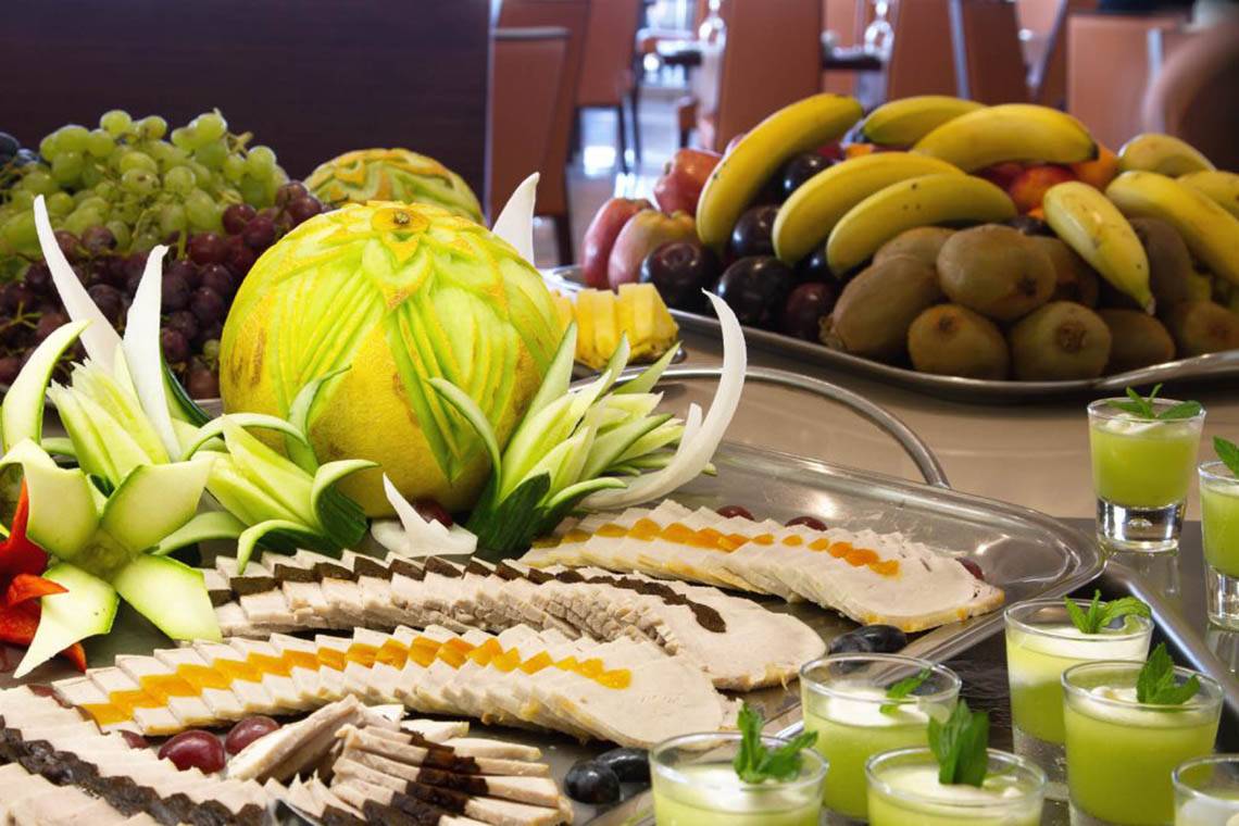 Ein Buffettisch mit einer Vielzahl von Früchten, Fleischplatten und Getränken.
