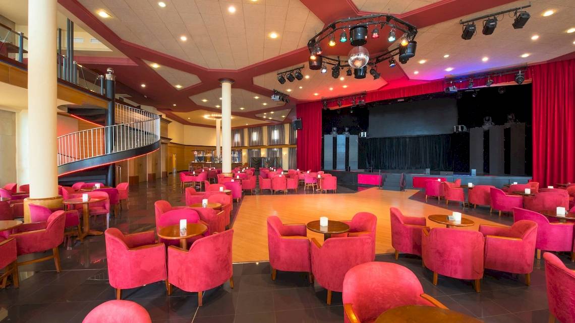 Innenansicht des Iberostar Selection Anthelia Hotels mit roter Bestuhlung, zentraler Tanzfläche und Bühne.