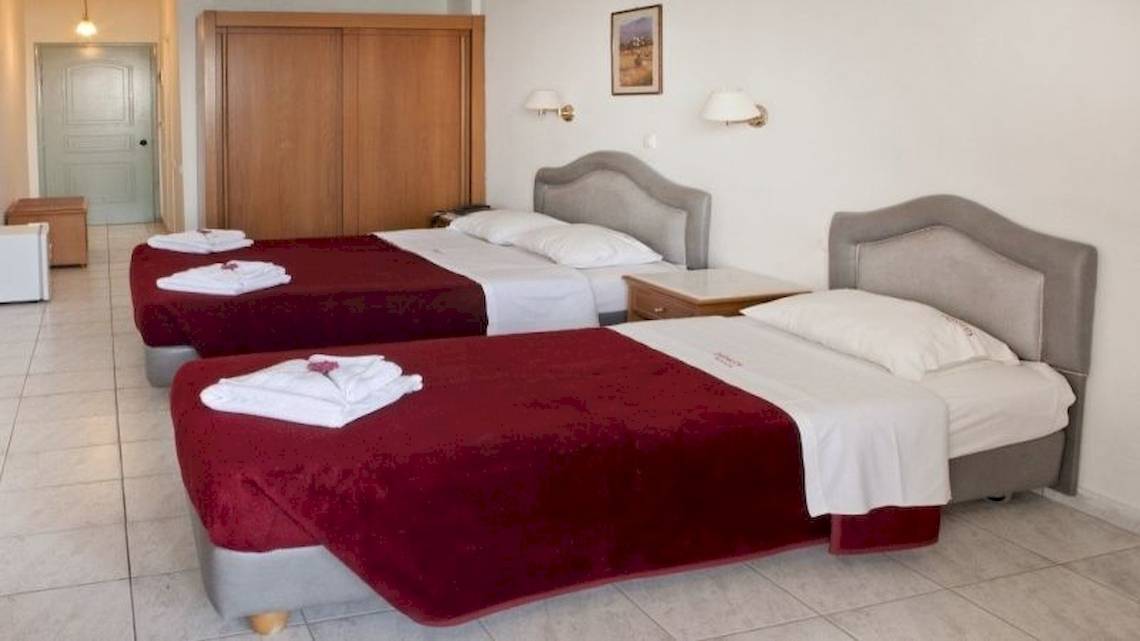 Zwei Doppelbetten mit roten und weißen Bettdecken in einem Hotelzimmer.