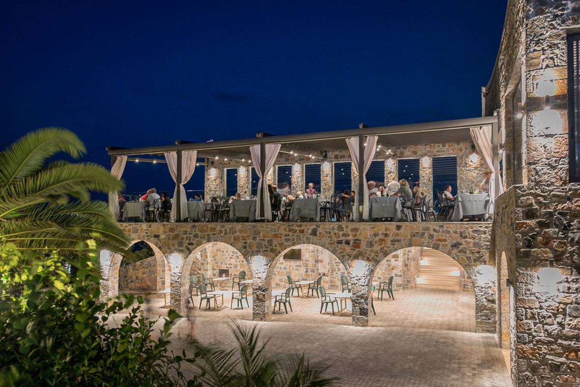 Terrasse des Nana Golden Beach Hotels bei Nacht mit Gästen, die draußen sitzen.