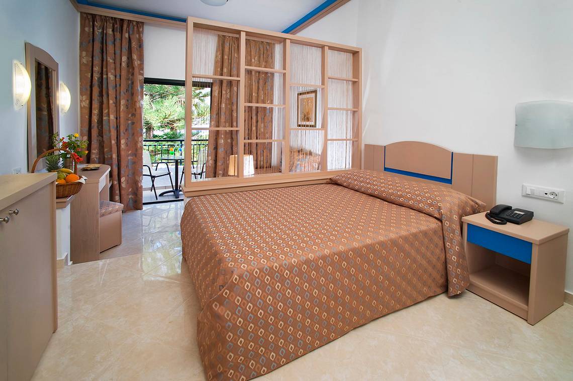 Ein Bett im Zimmer des Nana Golden Beach Hotels mit einem Balkon im Hintergrund.