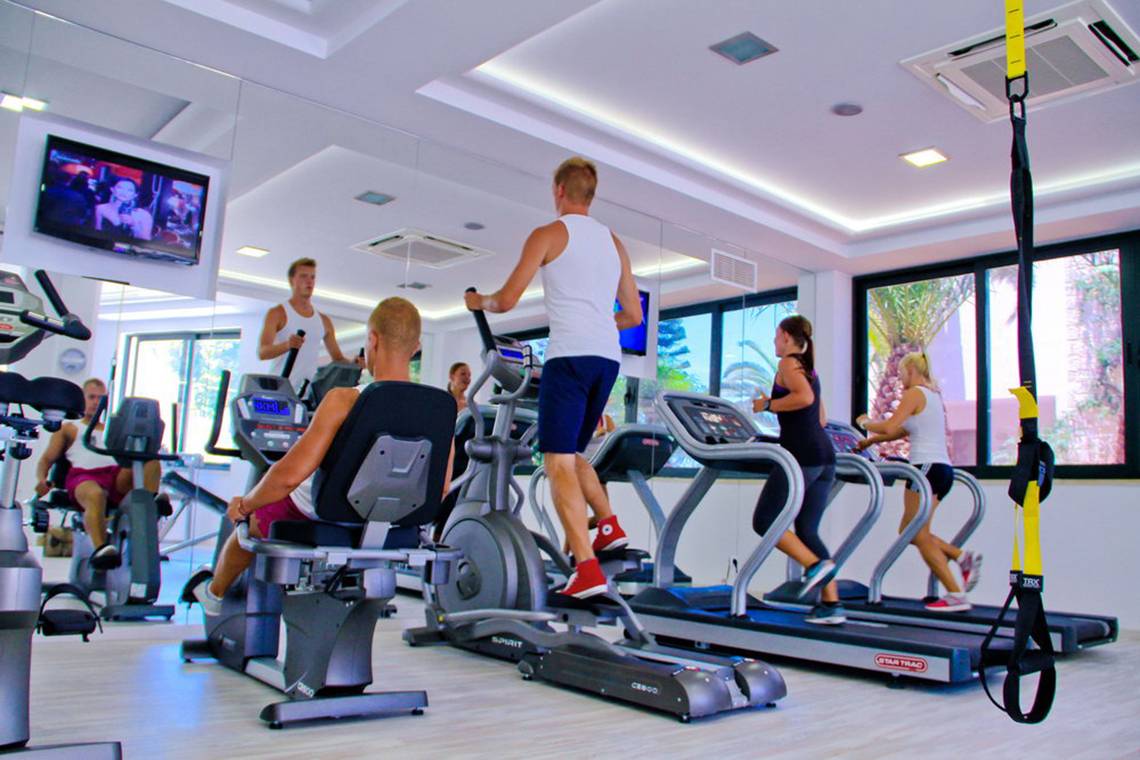 Fitnessstudio im Nana Golden Beach Hotel mit mehreren Personen auf Laufbändern und anderen Geräten.