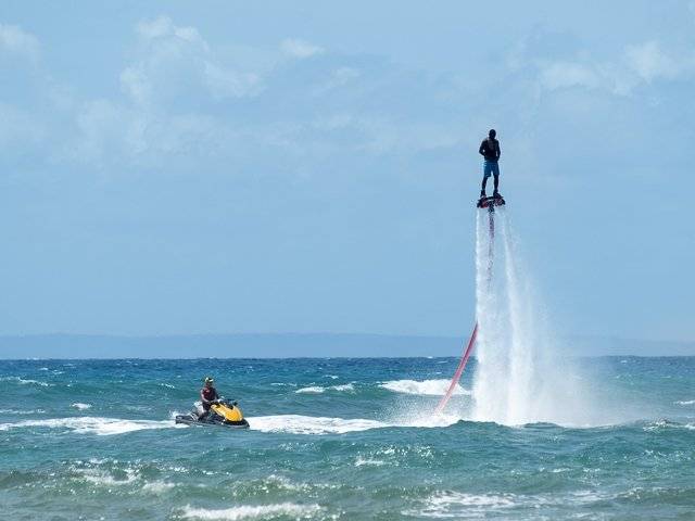 Zwei Personen genießen Wasserspaß im Ozean mit Jetskis und Fontänen.