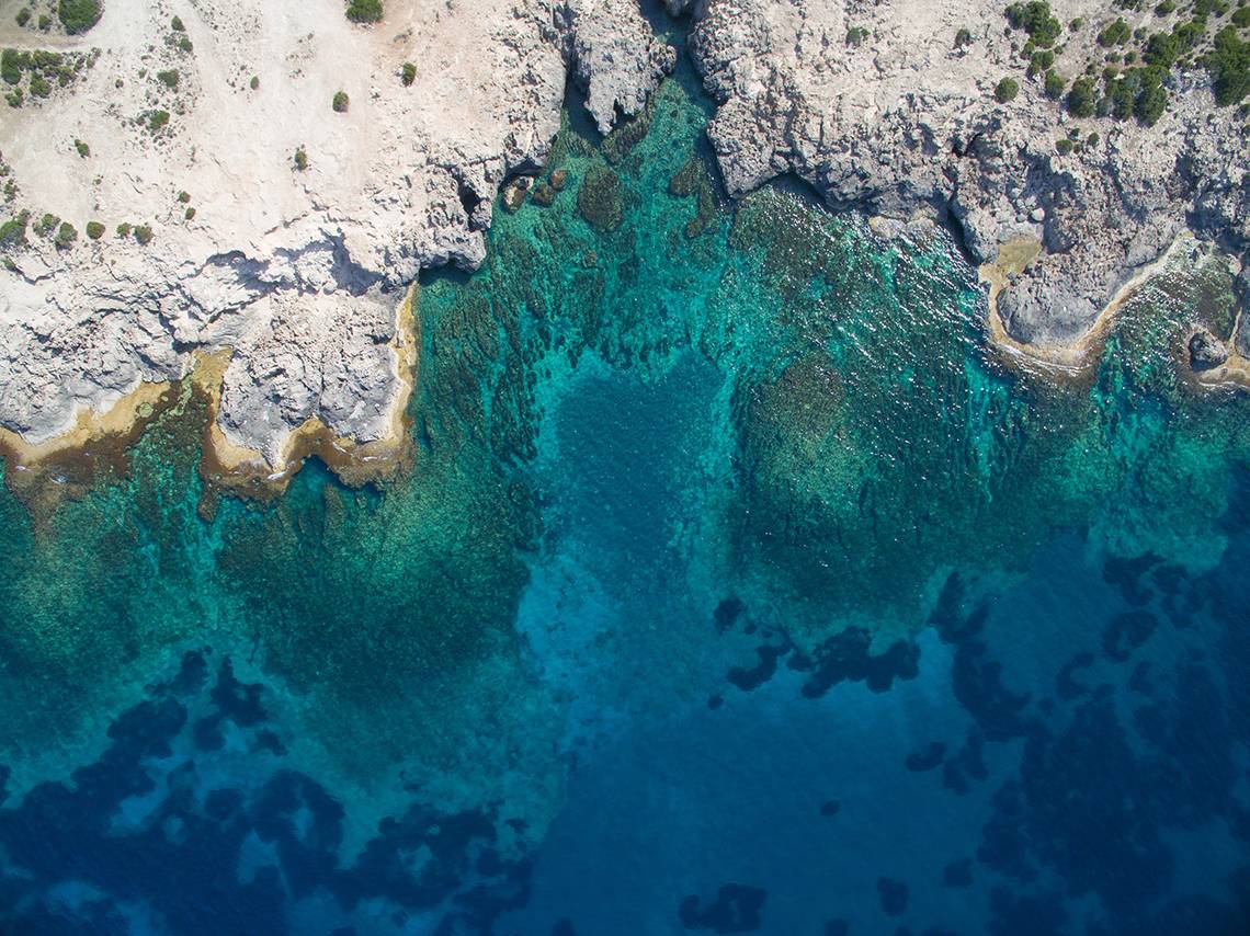 Luftaufnahme des blauen Wassers und felsigen Ufers bei Louis Paphos Breeze Hotel.