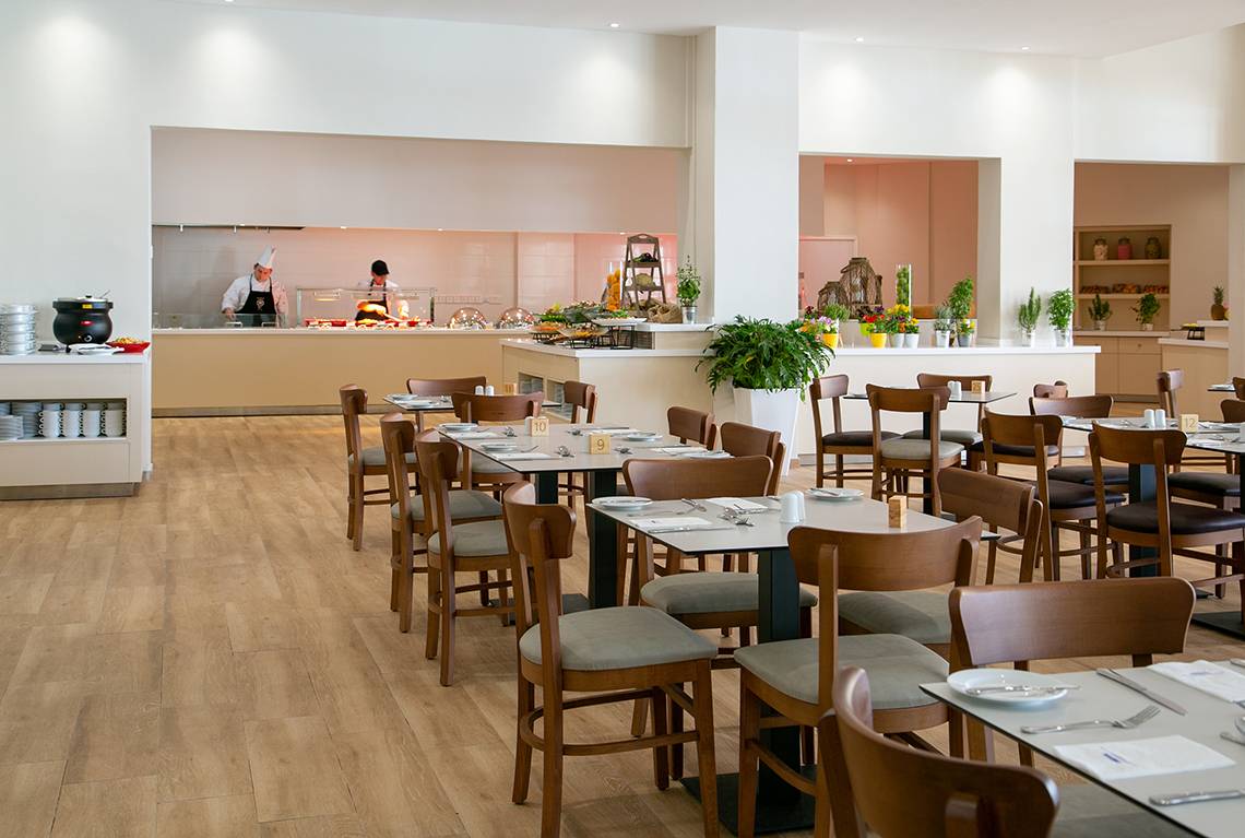 Restaurant im Louis Paphos Breeze Hotel mit Köchen und gedeckten Tischen.