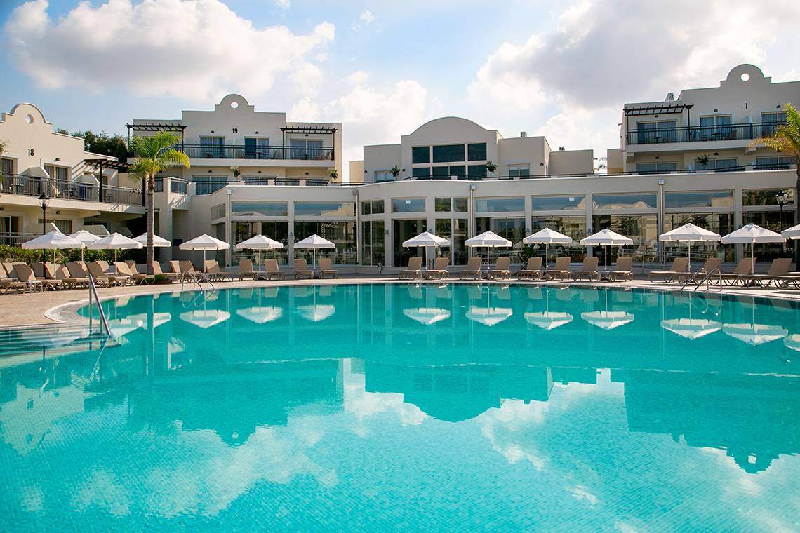 Außenpool des Louis Paphos Breeze Hotels mit Sonnenliegen und Schirmen