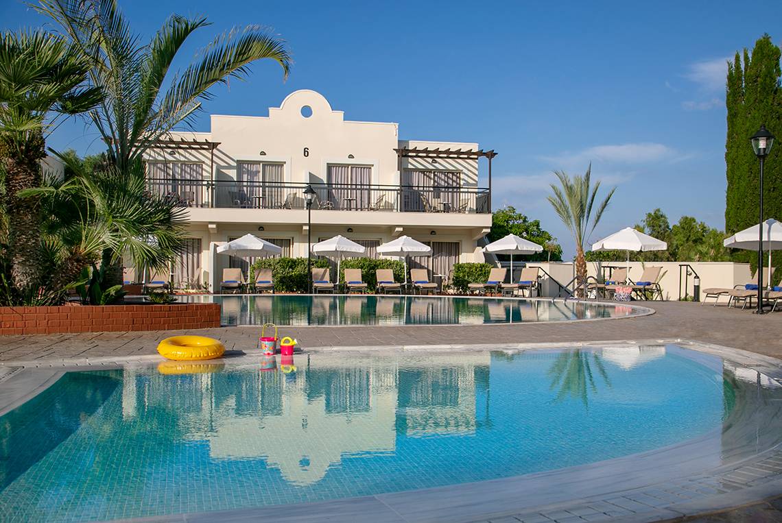Außenansicht des Louis Paphos Breeze Hotels mit Swimmingpool, Sonnenliegen und Schirmen